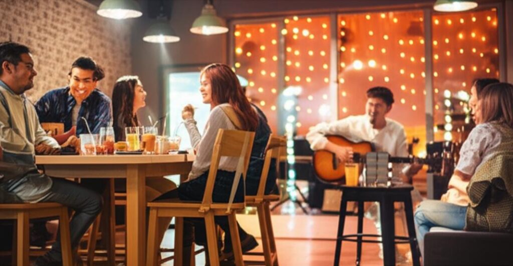 Khung cảnh ấm cúng tại quán cafe acoustic với mọi người đang thưởng thức âm nhạc sống.