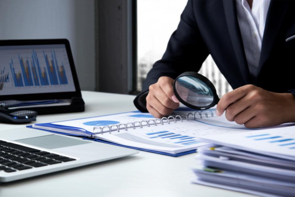 Kiểm toán viên tập trung làm việc với tài liệu tài chính và máy tính.