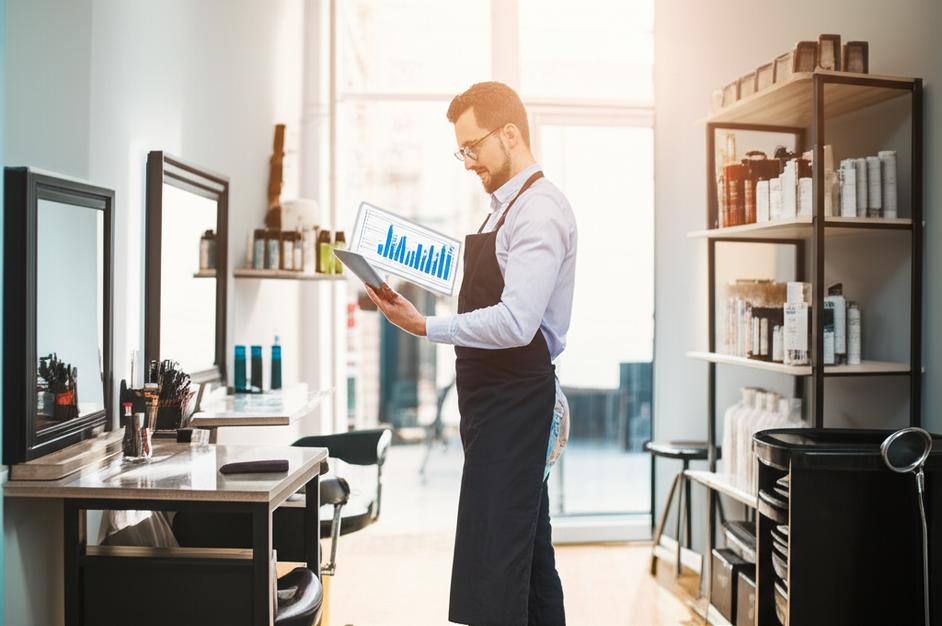 Quản lý salon tóc xem báo cáo hiệu quả kinh doanh trên máy tính bảng.